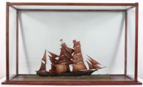 A Scratch built model of a three masted ship on a choppy sea, in a mahogany stained display cabinet,