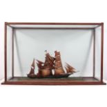 A Scratch built model of a three masted ship on a choppy sea, in a mahogany stained display cabinet,