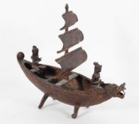 A Balinese metal model of a sailing boat with two figures and a dragon head prow,