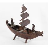 A Balinese metal model of a sailing boat with two figures and a dragon head prow,