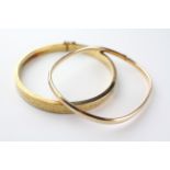 A collection of two yellow metal hollow bangles with engraved design.
