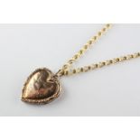 An ornate rose metal heart locket pendant suspended from a yellow gold 18 inch belcher chain.