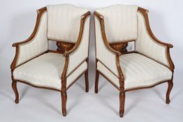 A pair of Edwardian walnut and inlaid fauteuils, upholstered, arched back above scrolling arms,