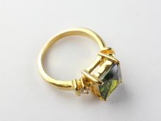 A yellow metal dress ring set with green and white stones. Tested as gold plated. Size: P ½ 6.