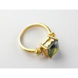 A yellow metal dress ring set with green and white stones. Tested as gold plated. Size: P ½ 6.