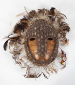 Tribal Art : A Lega mask, of shells and feathers applied to a tortoiseshell, 25cm high (total,