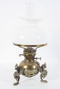 A Victorian brass oil lamp, the reservoir on three griffin legs, with a white glass shade,