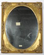 A French 19th century style mirror, the oval plate inside a gilt frame with foliate spandrils,