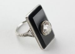 A white metal onyx panel ring centrally set with a transitional cut diamond estimated to weigh 1.