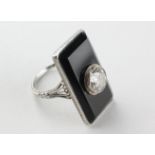 A white metal onyx panel ring centrally set with a transitional cut diamond estimated to weigh 1.