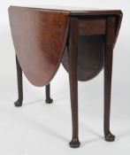 A George II style mahogany oval gate leg dining table, on tapering legs with pad feet,