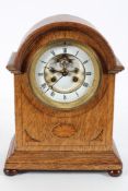 An oak cased mantel clock, late 19th century, the enamelled dial with visible escapement on a brass,