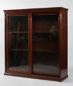 An Edwardian mahogany glazed bookcase with sliding double doors enclosing four adjustable shelves,