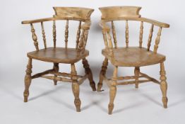 A pair of elm smokers chairs, with raised back, scrolled arms, turned spindles,