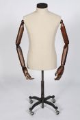 An antique style haberdashery/tailor's mannequin, having articulated arms, raised on a metal base,