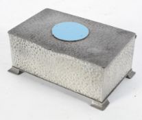 An English hammered pewter box and cover, with a blue enamelled medallion,