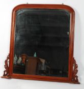 A mahogany over mantel mirror, the arched plate supported by scrolling foliate brackets,