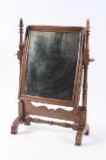 A Victorian walnut toilet mirror, the rectangular plate on turned supports,