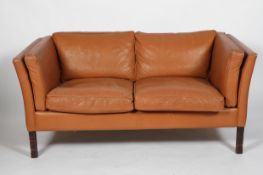 A Stouby late 20th Century tan leather upholstered two seat sofa, Danish,