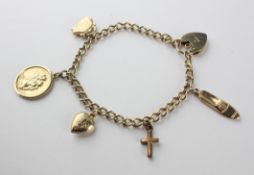A yellow metal curb link bracelet fitted with five assorted charms and padlock clasp.