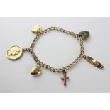 A yellow metal curb link bracelet fitted with five assorted charms and padlock clasp.