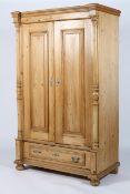 A Continental pine wardrobe, the pair of doors flanked by columns and above a single drawer,