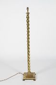 A polished brass standard lamp, the twisting column on a stepped square base and lion paw foot,