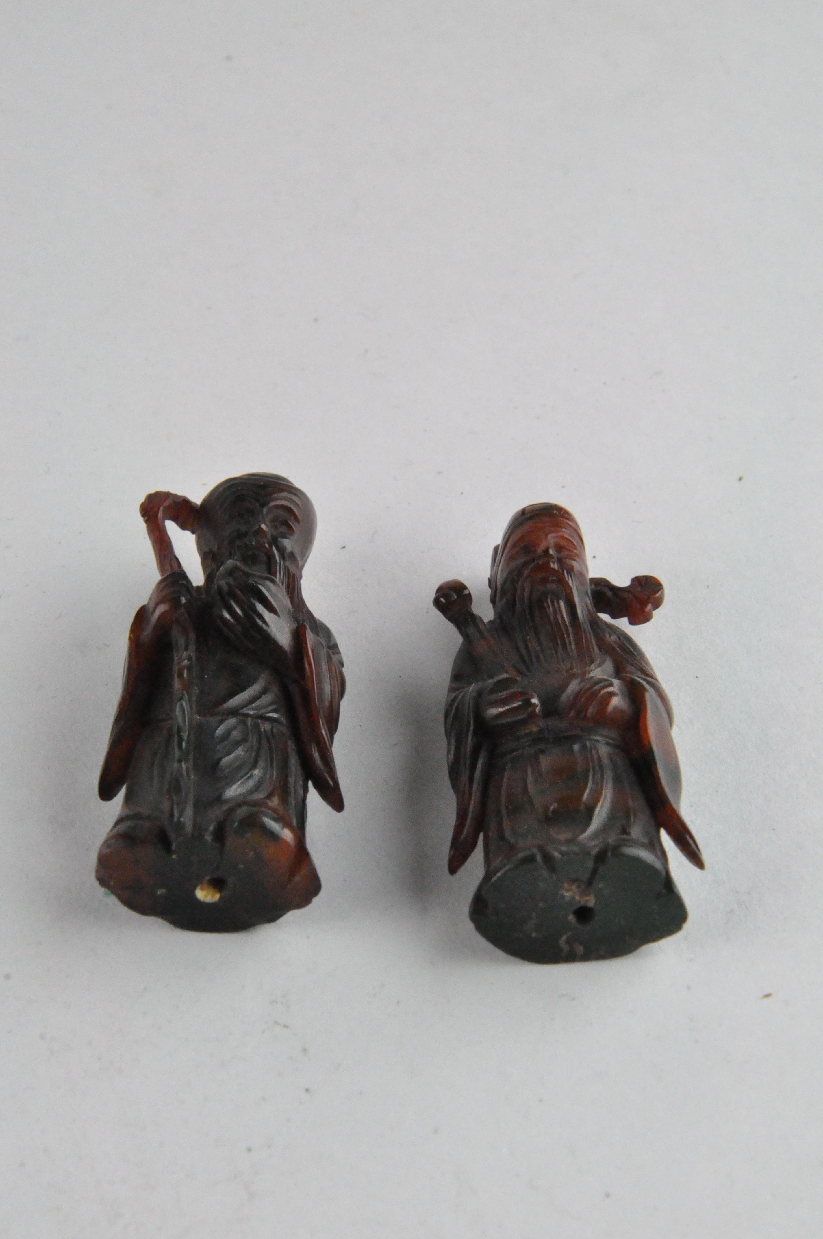 A group of three Chinese amber style figures of Immortals, standing on a carved wood base, - Image 8 of 9