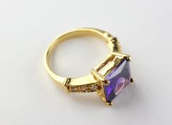 A yellow metal dress ring set with purple and white stones. Tested as gold plated. Size O 6.