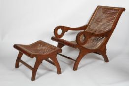 An Anglo Indian hardwood and caned steamer chair and stool, with scrolling arms and legs,