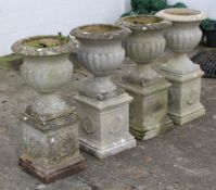 A set of four reconstituted stone urns, with reeded decoration,