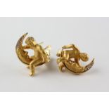 A yellow metal pair of earrings stylized as a cherub and moon