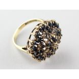 A large floral cluster ring set with sapphires and single cut diamonds.