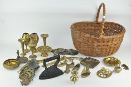 A wicker basket containing an assortment of metalware, including horse brasses, ash trays,