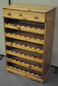 A mid century pine wine rack, with single drawer to top over six shelves,