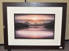 A modern framed picture depicting a sunset over a lake,