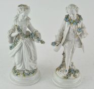 A pair of male and female porcelain figures, holding garlands of forget-me-nots,