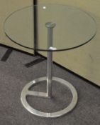 A modern glass topped coffee table of circular form on metal stand,
