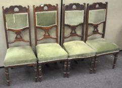 A set of four oak dining chairs, with upholstered seats and backs, raised on turned supports,