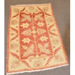 A Pakistan wool rug with cream, ochre, red and grey foliate decoration,