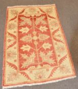 A Pakistan wool rug with cream, ochre, red and grey foliate decoration,
