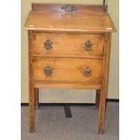 An early 20th century two drawer oak hall unit with carved motifs to the legs and back,