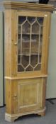 A large pine corner display cabinet, with a single glazed door above a single door cupboard,