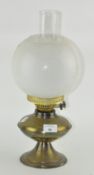 A vintage brass oil lamp with glass shade and funnel,