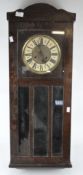 A 20th century stained wood wall clock, the dial with Roman Numerals denoting hours,