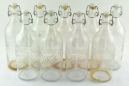 A group of nine glass storage bottles with stoppers,