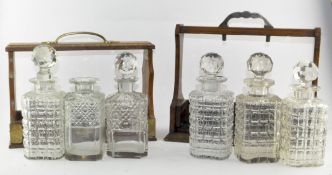 Two early 20th century oak three bottle tantalus with six assorted spirit decanters and five