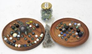 A collection of marbles of varying sizes along with two marble solitaire boards
