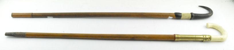 Two walking canes, one with ivory coloured and brass handle, the other with carved horn style mount,