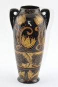 A brown glazed twin handled vase decorated throughout with floral motifs,